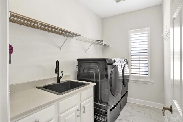 clothes washing area featuring separate washer and dryer, sink, and cabinets