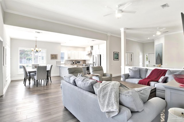 living room with ceiling fan with notable chandelier, wood-type flooring, and ornamental molding