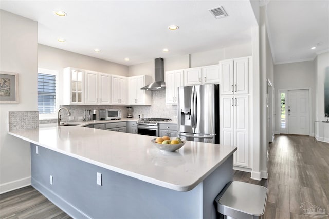 kitchen featuring appliances with stainless steel finishes, wall chimney range hood, and white cabinets