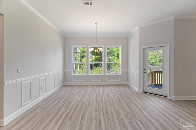 interior space featuring wainscoting, an inviting chandelier, crown molding, and light wood-style flooring