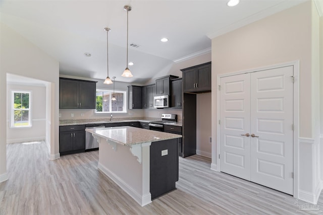 kitchen with a sink, light wood finished floors, a kitchen island, and appliances with stainless steel finishes