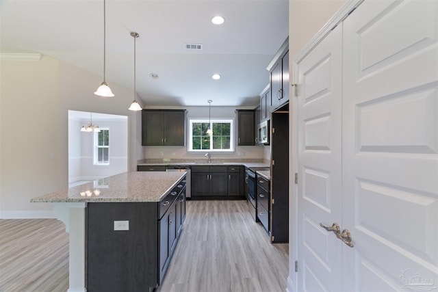 kitchen featuring a sink, light wood finished floors, a center island, and appliances with stainless steel finishes