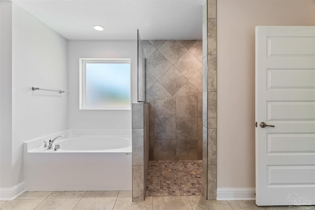 bathroom featuring a garden tub, baseboards, tile patterned flooring, and a walk in shower