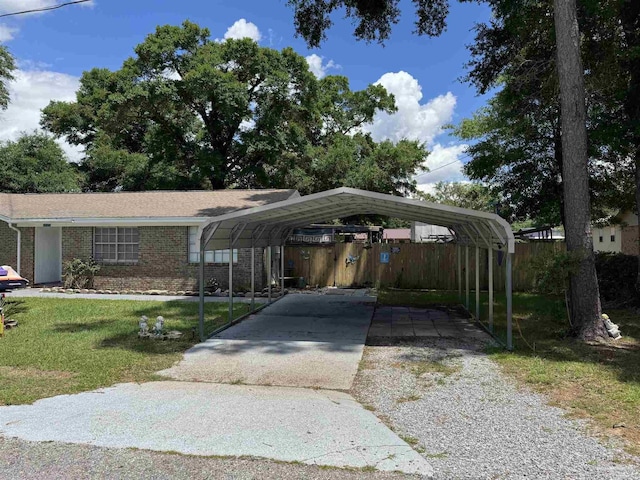 view of front of home with driveway, a detached carport, a front yard, and brick siding