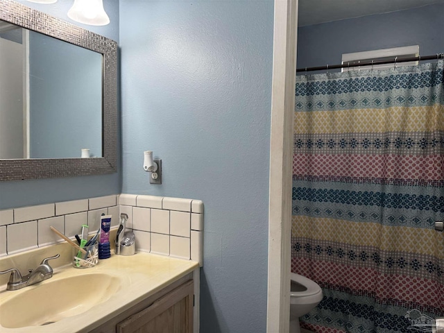 full bathroom featuring toilet, vanity, a shower with shower curtain, a textured wall, and tasteful backsplash