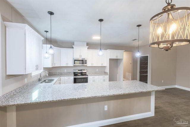 kitchen featuring stainless steel appliances, a peninsula, dark wood-style flooring, a sink, and light stone countertops