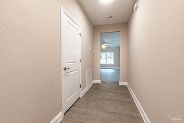 hallway featuring baseboards, visible vents, and wood finished floors