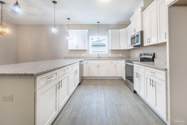 kitchen featuring light wood finished floors, white cabinets, appliances with stainless steel finishes, light stone counters, and a peninsula