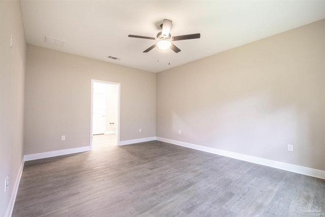 spare room with a ceiling fan, wood finished floors, visible vents, and baseboards