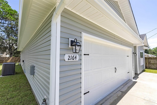 garage featuring central AC, concrete driveway, and fence