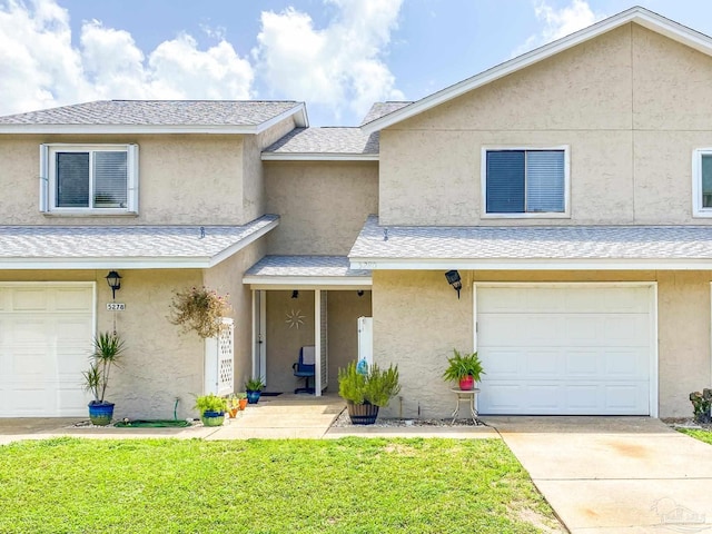 townhome / multi-family property with a garage, a shingled roof, and stucco siding