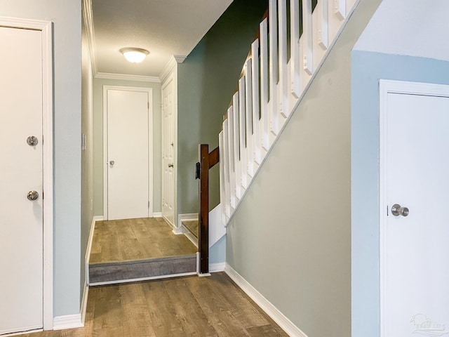 interior space with baseboards, crown molding, stairway, and wood finished floors