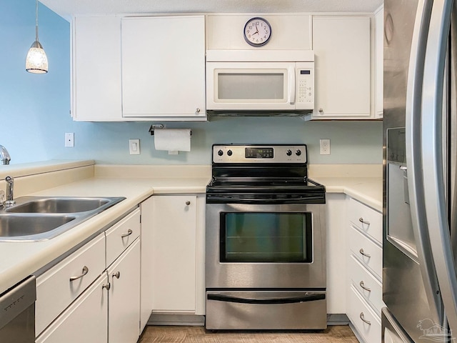 kitchen with white cabinets, stainless steel appliances, a sink, and light countertops