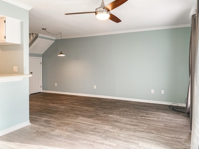 empty room featuring a ceiling fan, crown molding, baseboards, and wood finished floors