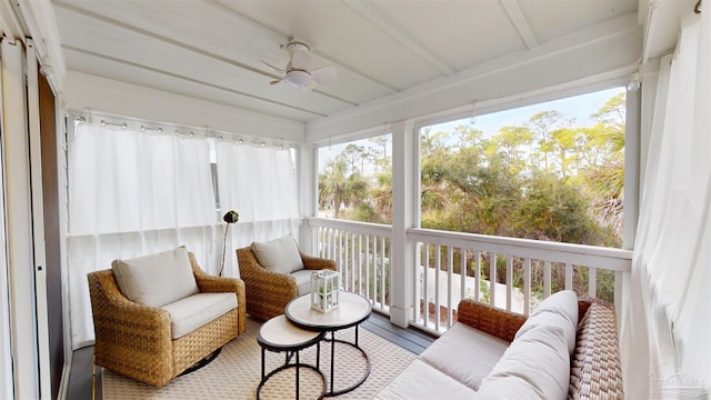 sunroom / solarium featuring beamed ceiling and ceiling fan