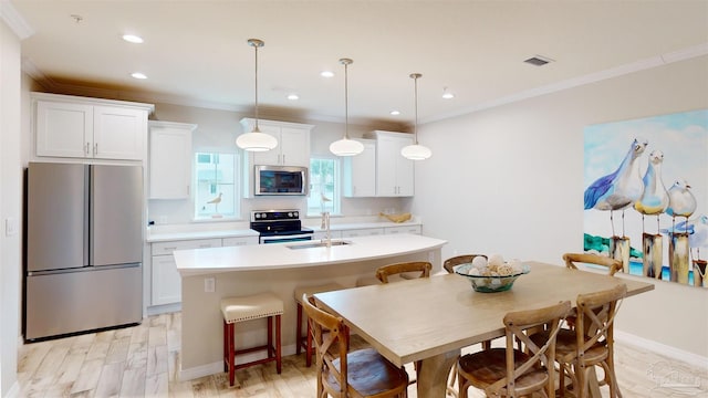 kitchen featuring pendant lighting, stainless steel appliances, white cabinets, and a center island with sink