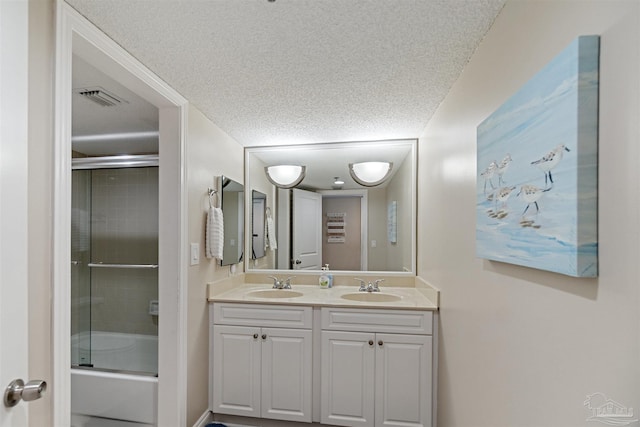 bathroom with vanity, enclosed tub / shower combo, and a textured ceiling