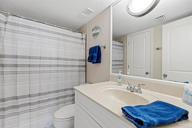 bathroom with vanity, toilet, a textured ceiling, and walk in shower