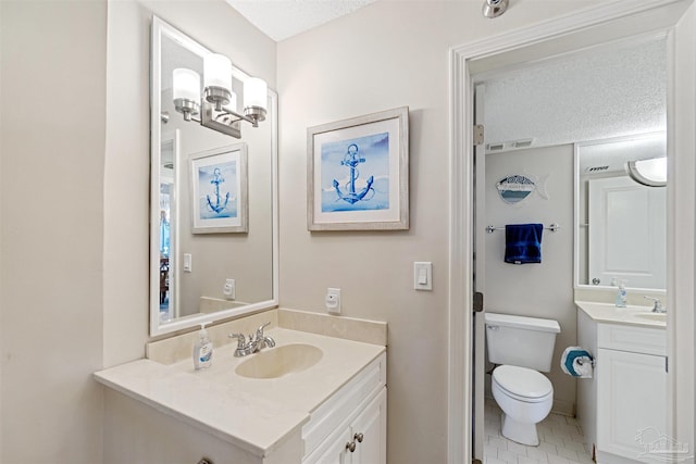 bathroom with vanity, a textured ceiling, toilet, and tile patterned floors