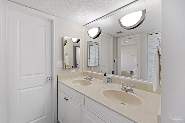 bathroom featuring vanity, a textured ceiling, and toilet