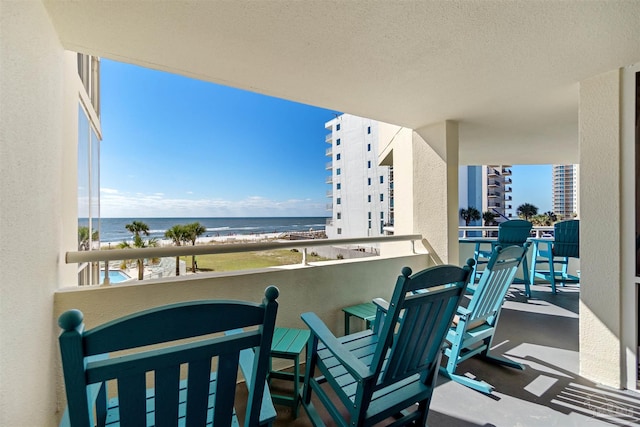 balcony featuring a water view and a beach view