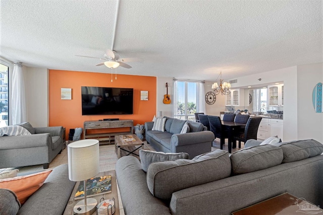 living room with a textured ceiling and ceiling fan with notable chandelier