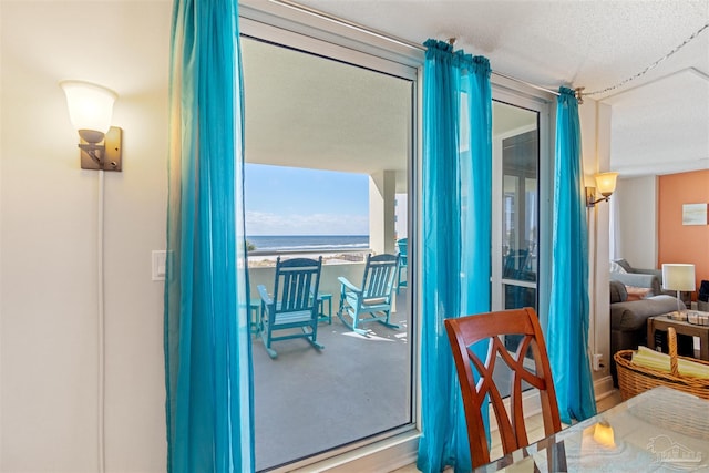 dining area featuring a water view and a textured ceiling