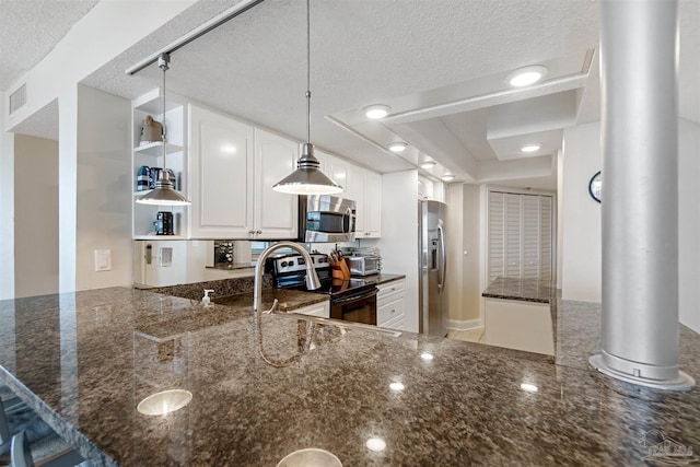 kitchen featuring kitchen peninsula, white cabinets, a textured ceiling, dark stone countertops, and stainless steel appliances