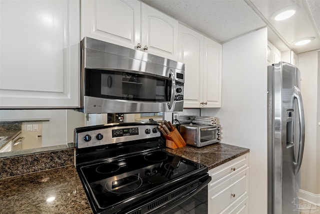 kitchen featuring a textured ceiling, white cabinetry, stainless steel appliances, and dark stone countertops