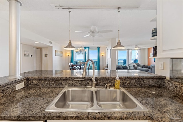 kitchen featuring white cabinets, a textured ceiling, ceiling fan with notable chandelier, pendant lighting, and sink