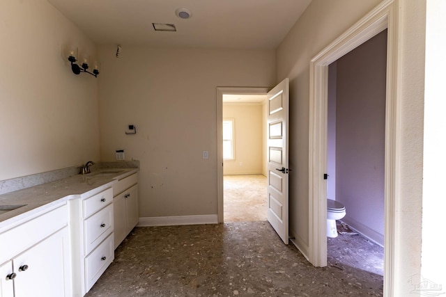 bathroom featuring toilet, baseboards, and a sink