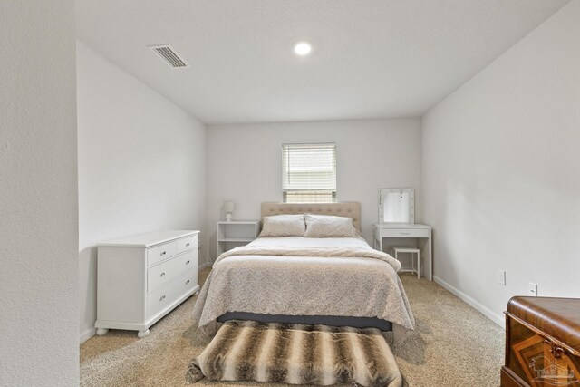 bedroom featuring baseboards, visible vents, and light colored carpet