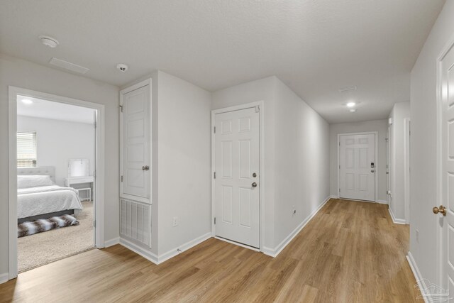 hall with baseboards and light wood finished floors
