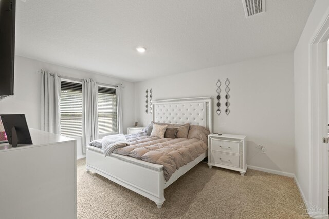 bedroom with light carpet, baseboards, visible vents, and a textured ceiling