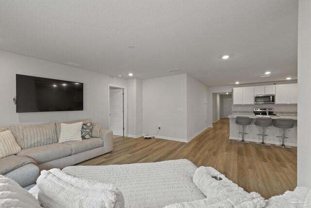 living room featuring light wood-type flooring, baseboards, and recessed lighting