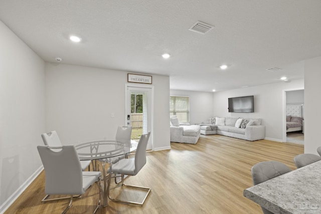 dining room with baseboards, visible vents, and light wood finished floors