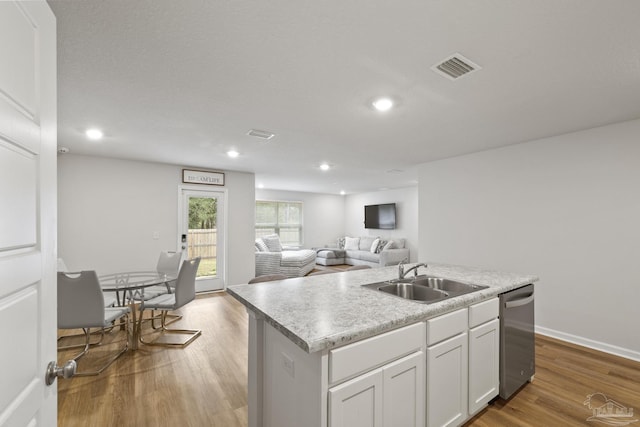 kitchen featuring light wood finished floors, open floor plan, a sink, an island with sink, and dishwasher