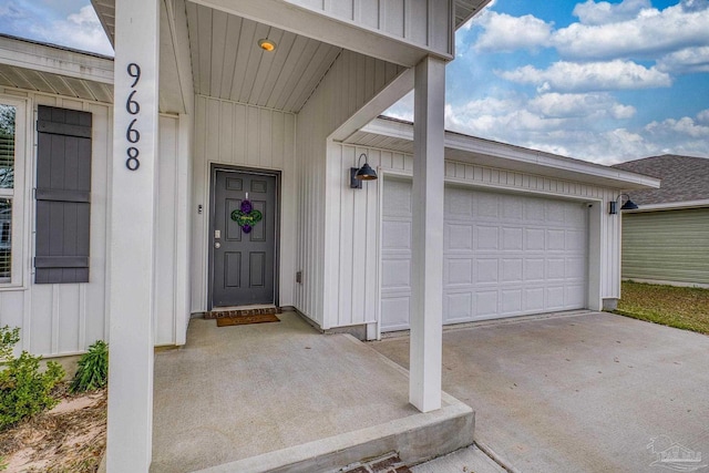 entrance to property featuring board and batten siding, driveway, and a garage