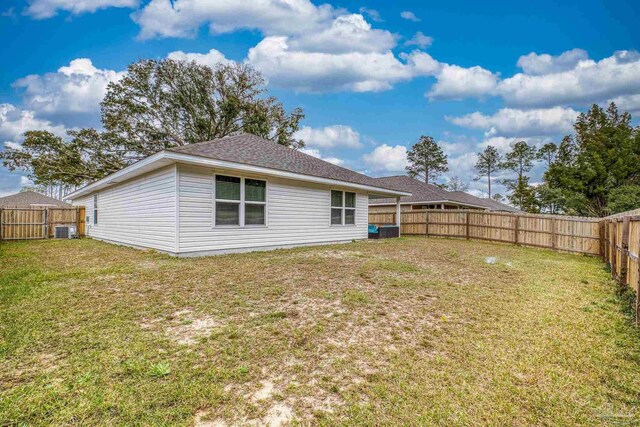 rear view of house featuring a fenced backyard, a yard, and central AC unit