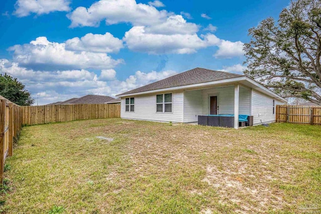 back of property with a fenced backyard, a shingled roof, and a yard