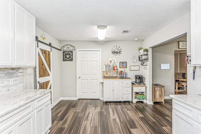 kitchen with a barn door, baseboards, decorative backsplash, and dark wood-style floors