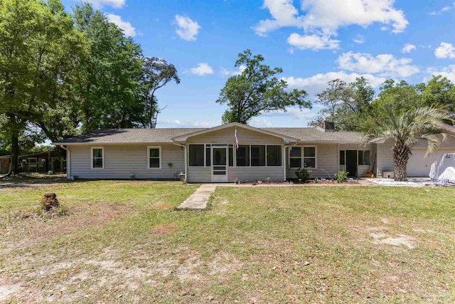 rear view of property featuring a sunroom, a chimney, and a lawn