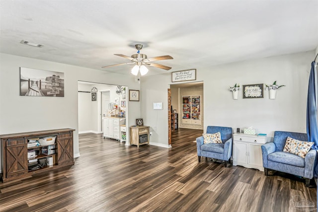 sitting room with visible vents, a ceiling fan, baseboards, and dark wood-style flooring