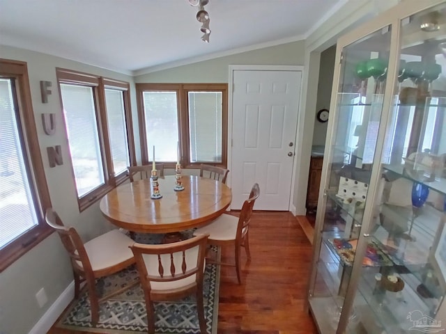 dining space featuring wood-type flooring, ornamental molding, and vaulted ceiling