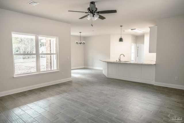 unfurnished living room featuring dark wood-style floors, baseboards, visible vents, and a sink