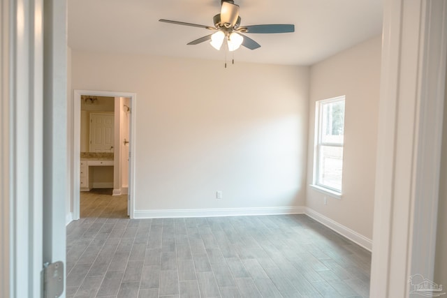 spare room with light wood finished floors, baseboards, and a ceiling fan