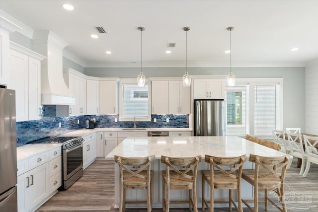 kitchen featuring white cabinets, a kitchen island, pendant lighting, and appliances with stainless steel finishes