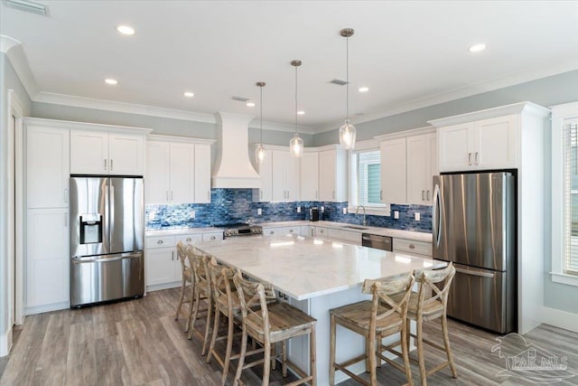 kitchen featuring sink, a center island, hanging light fixtures, premium range hood, and appliances with stainless steel finishes