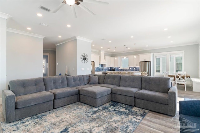 living room featuring ceiling fan, light hardwood / wood-style floors, and ornamental molding