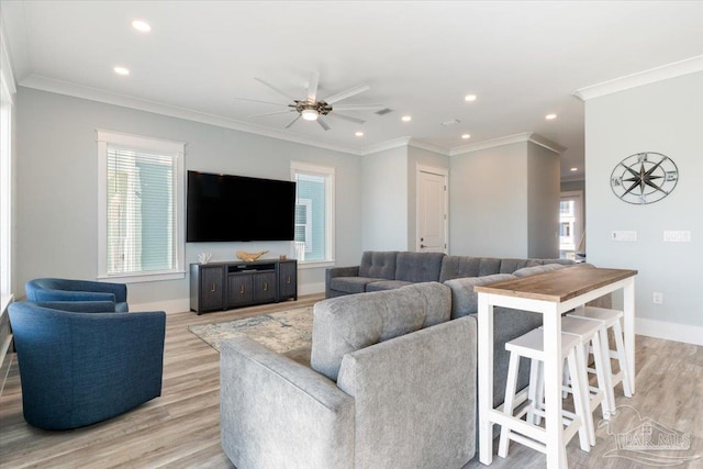 living room featuring crown molding, a healthy amount of sunlight, and light wood-type flooring